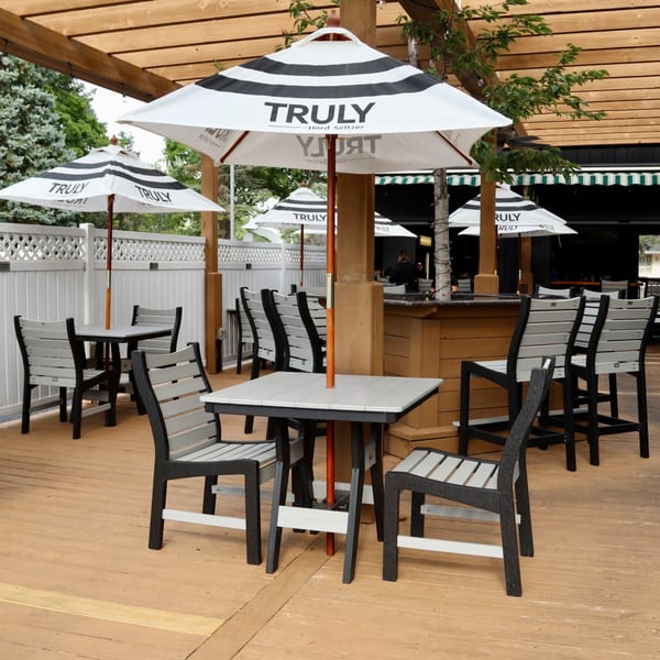Outdoor patio with wooden deck, black and white striped umbrellas, and gray and black tables and chairs.