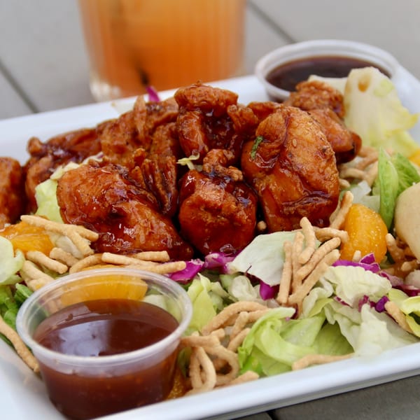 Sweet and sour chicken with lettuce, mandarin oranges, and crispy noodles, with dipping sauces.